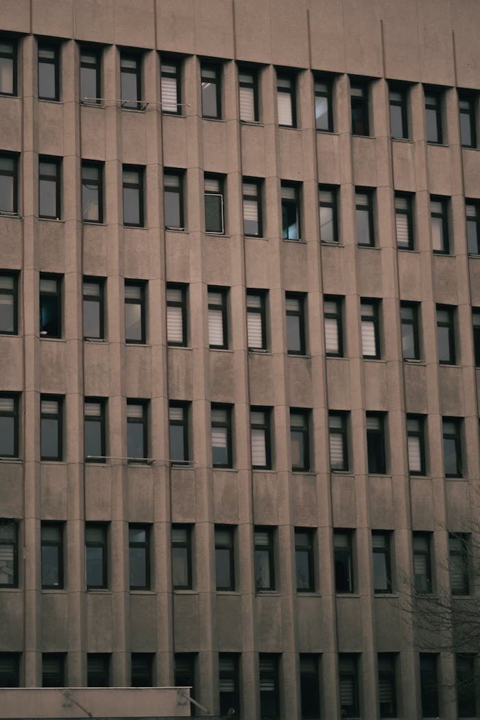 Detailed shot of a modern urban office building facade with repetitive patterns in subdued light.
